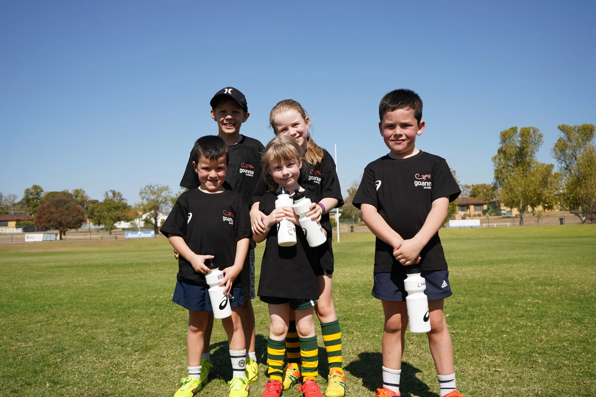 Group of kids holding drink bottles smiling at Goanna Academy clinic