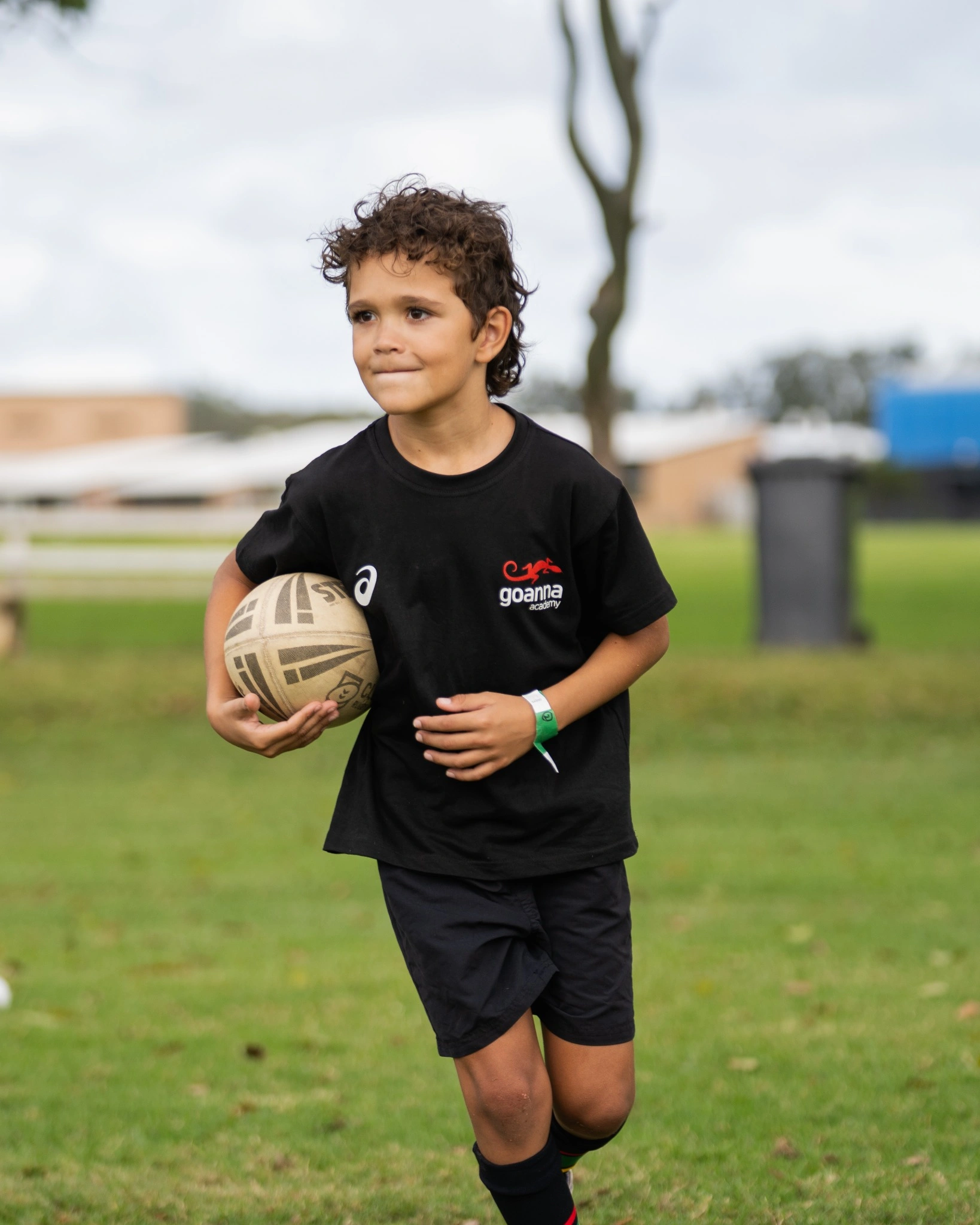 Boy running and carrying rugby ball with a smile